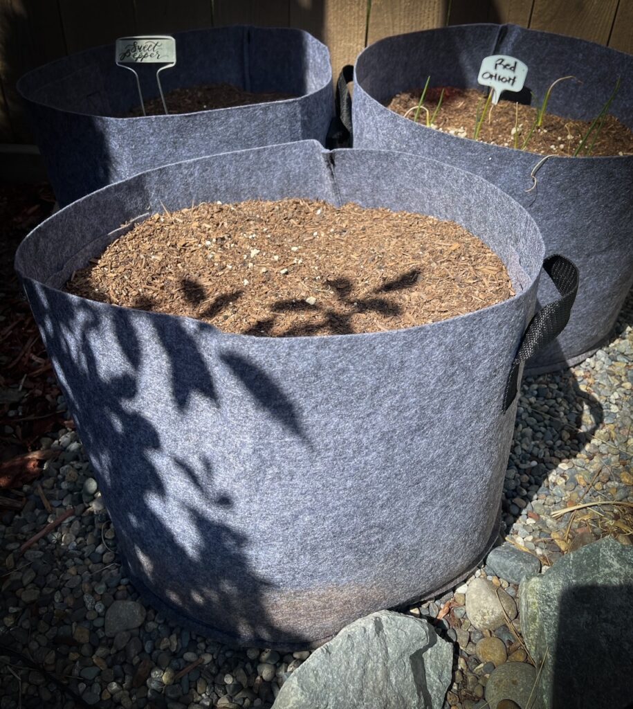 Favorite gardening Tools 16. Three of the best grow bags sitting on a pebble surface.